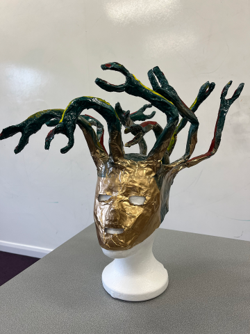 This model takes the form of a golden mask, topped with writhing metallic green snakes for hair.