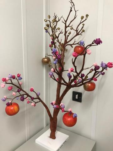 A model of a tree, whose brightly coloured apples and blossoms are beginning to turn to gold.